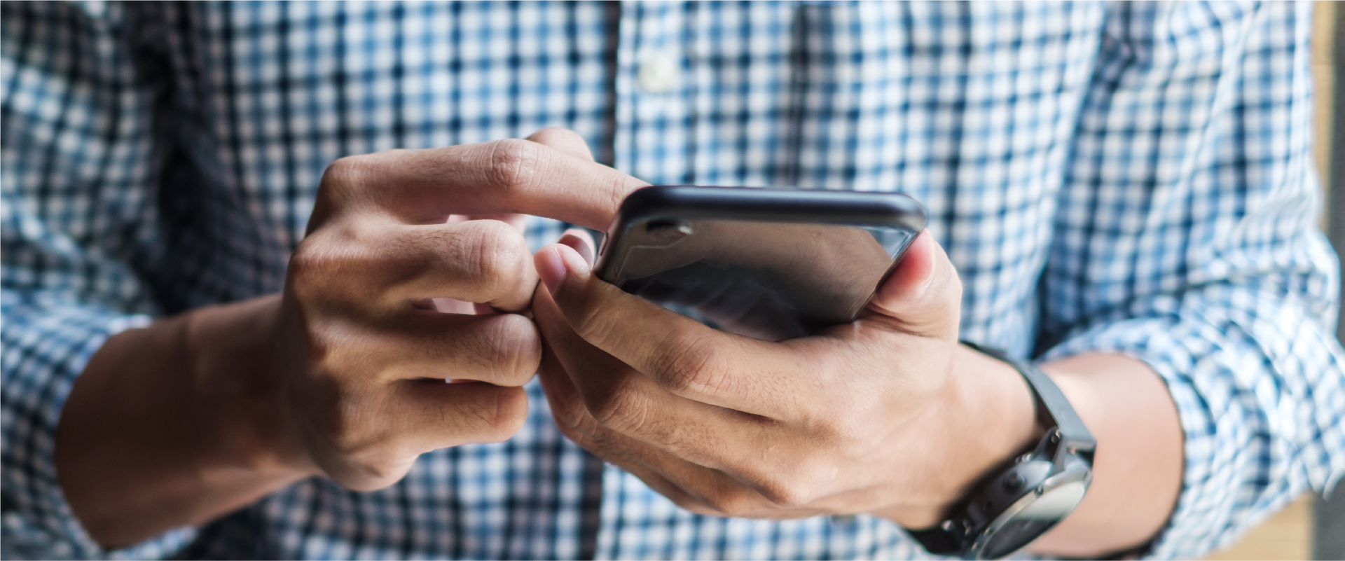 Someone scrolling through a smartphone. Image of chest, arms and hands holding phone.